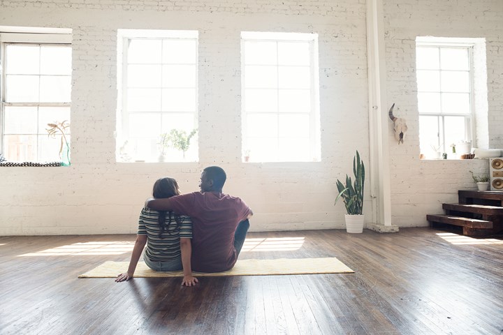 Couple sitting on rug in empty home