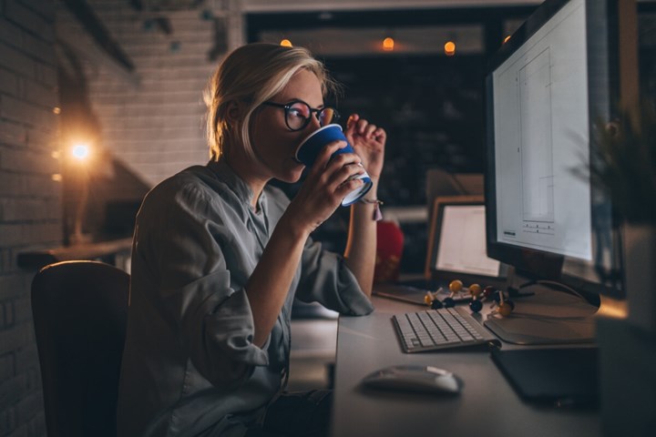 Une femme qui boit du café en travaillant sur l'ordinateur