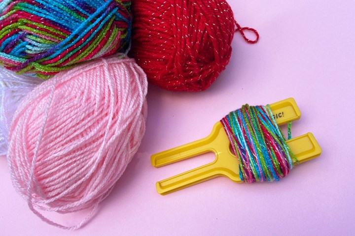 Lock yarn into your pom-pom maker. Wrap 20-30 times around your pom-pom spool then snip and repeat with all the remaining colours.
