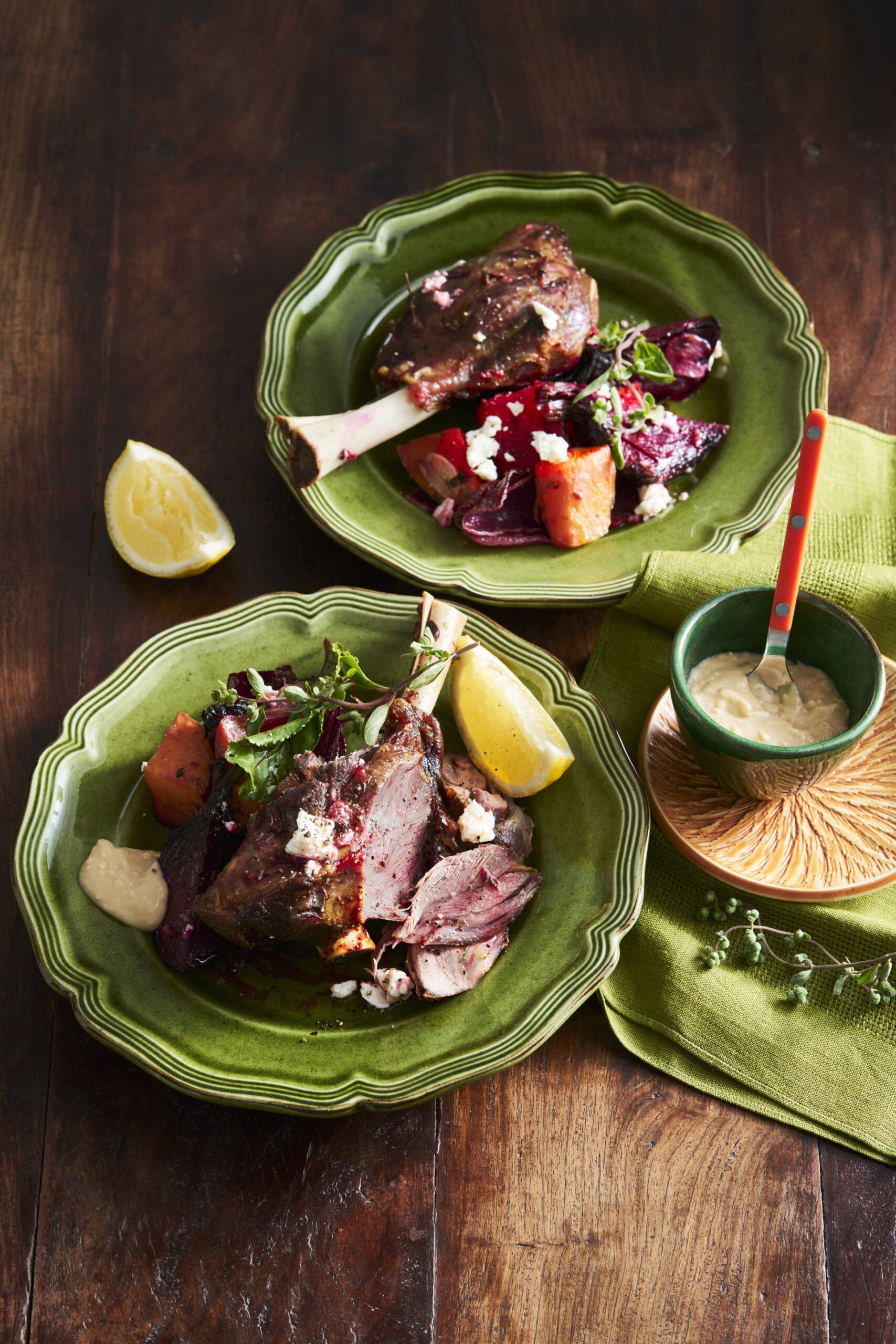 lamb shanks with beetroot and lemon wedges on bright green plate