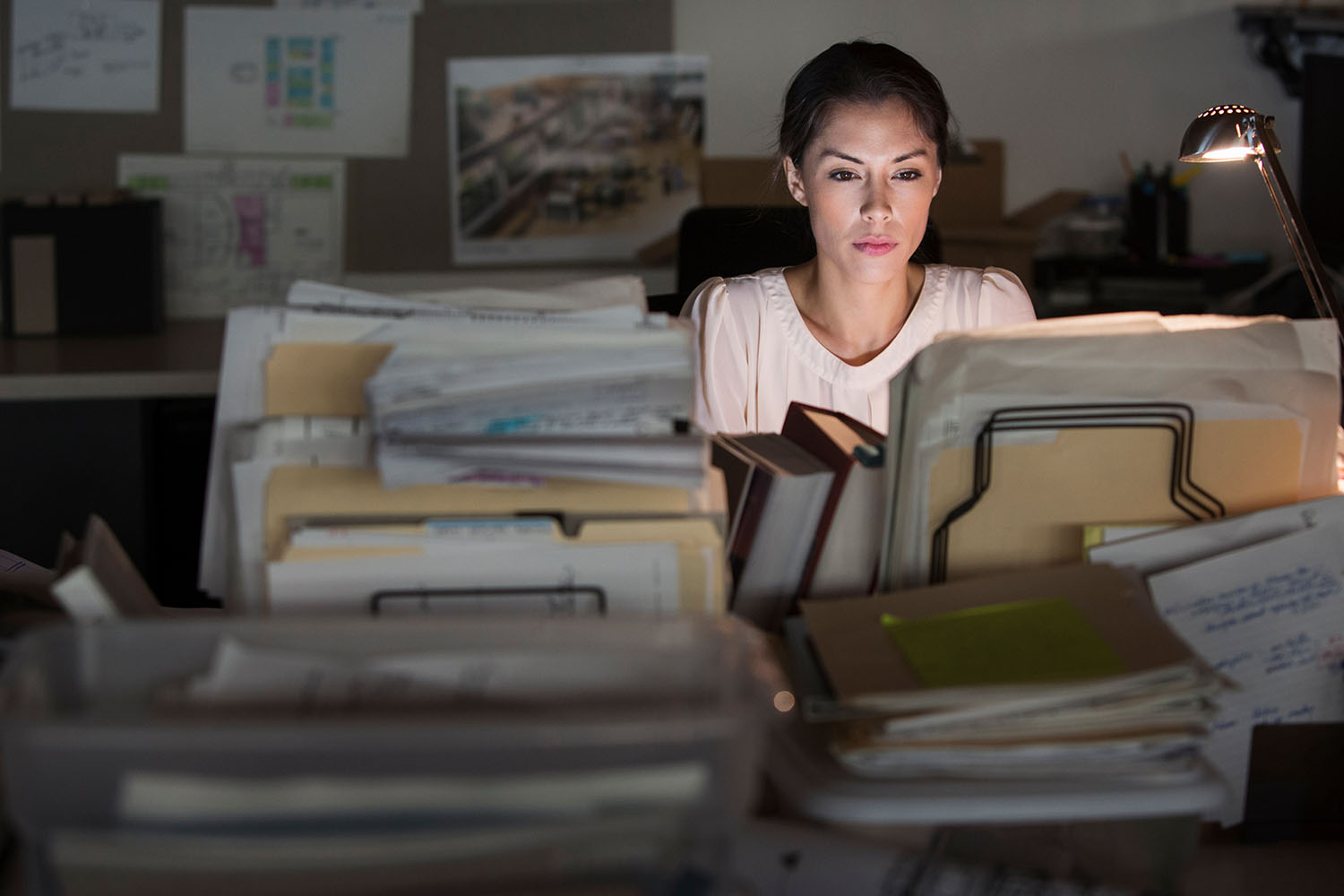 woman working at night behind stacks of files
