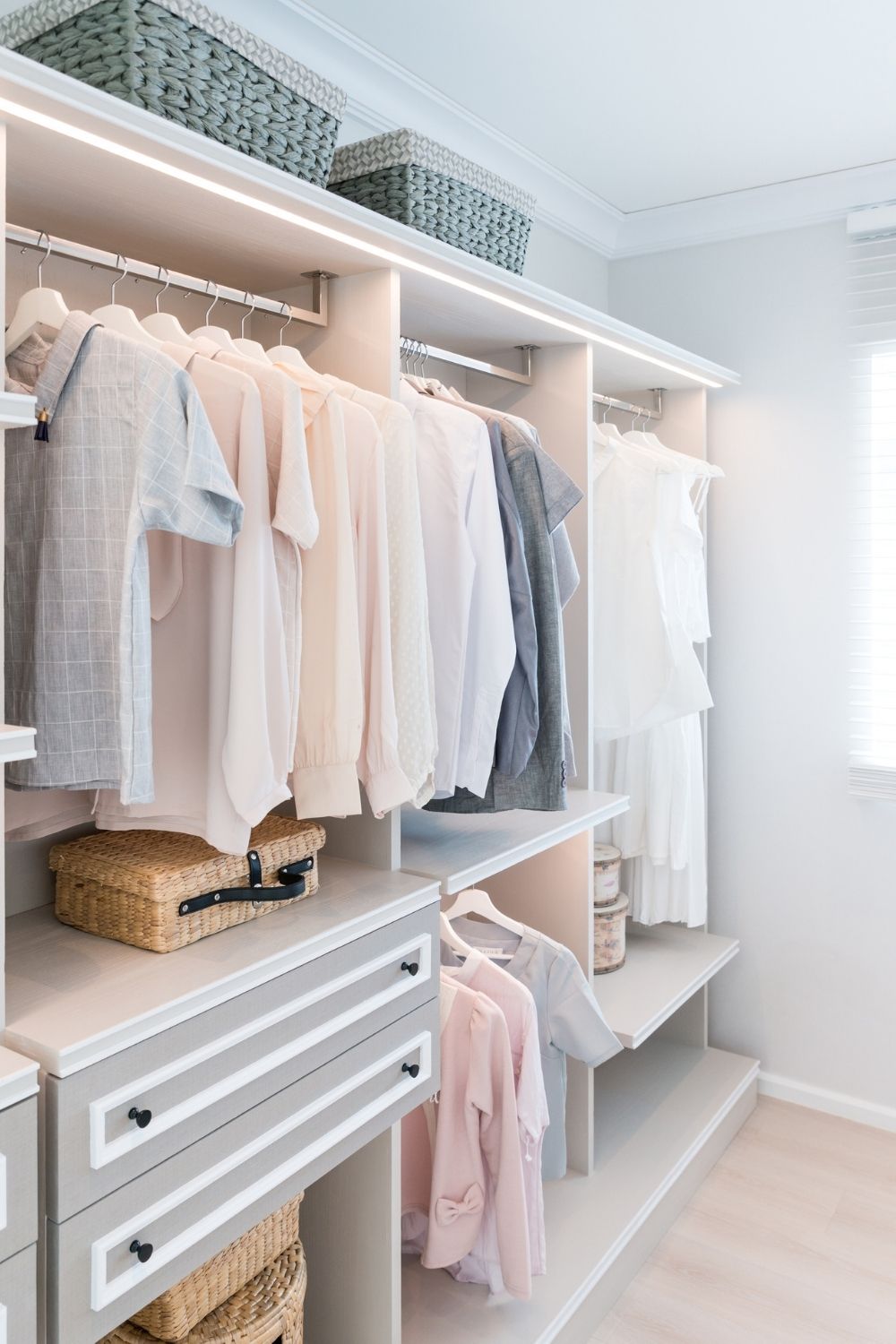 Grey wardrobe with pastel coloured clothing on hangers