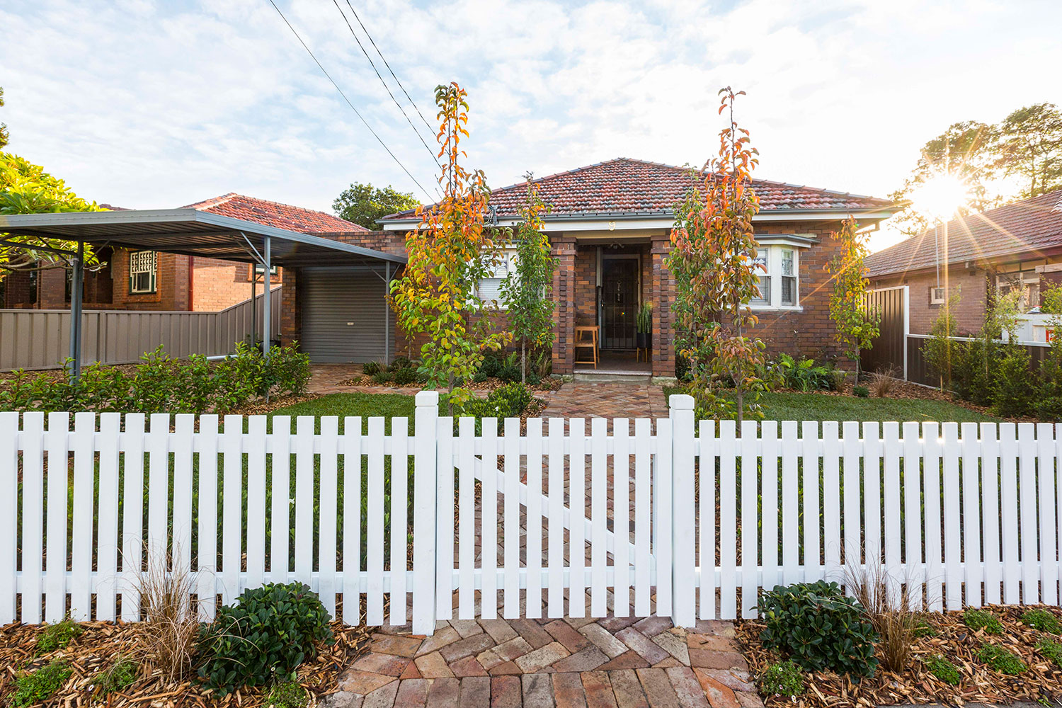 Brick home with tidy front garden and white picket fence