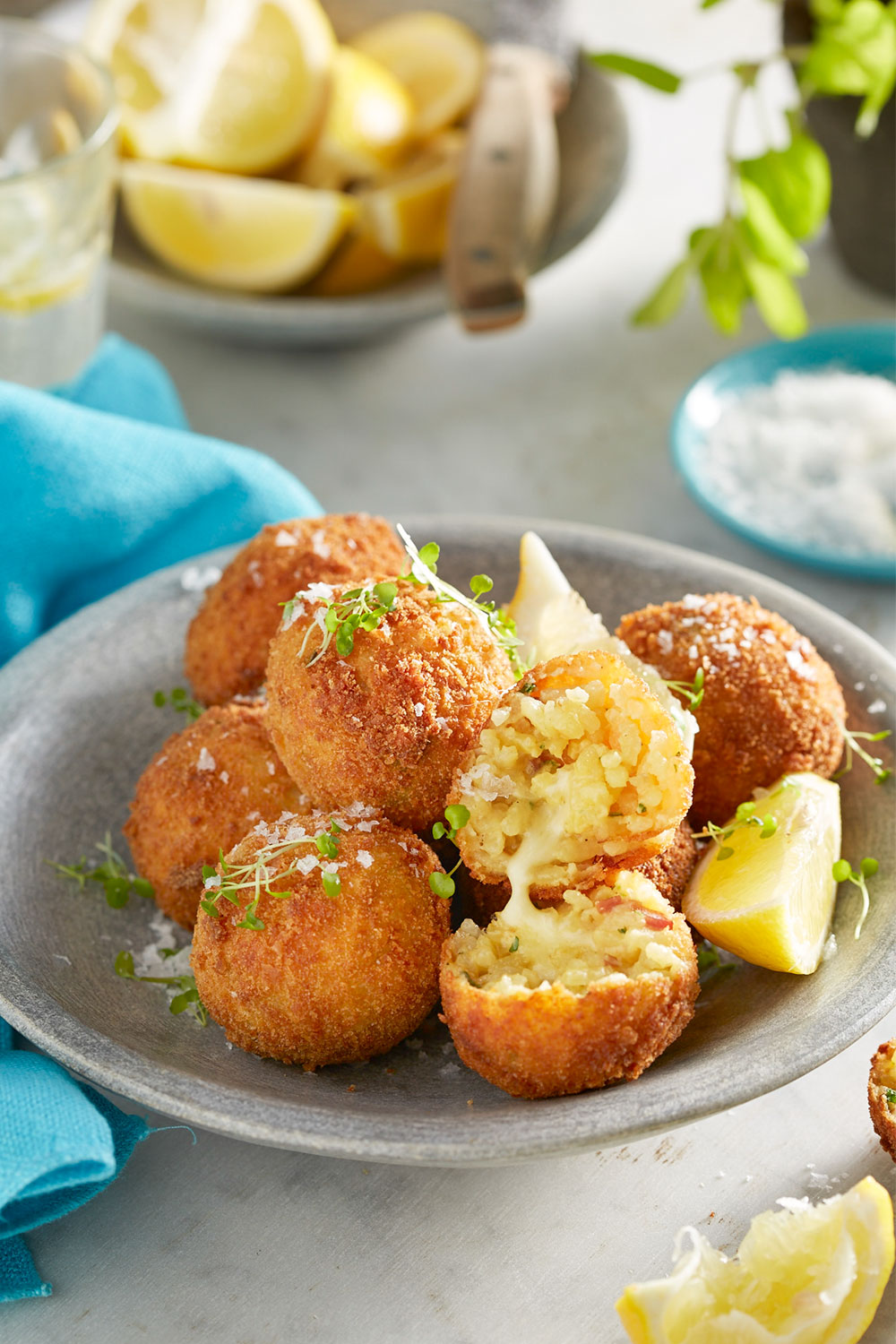 Arancini balls with one cut open and melted cheese on the inside